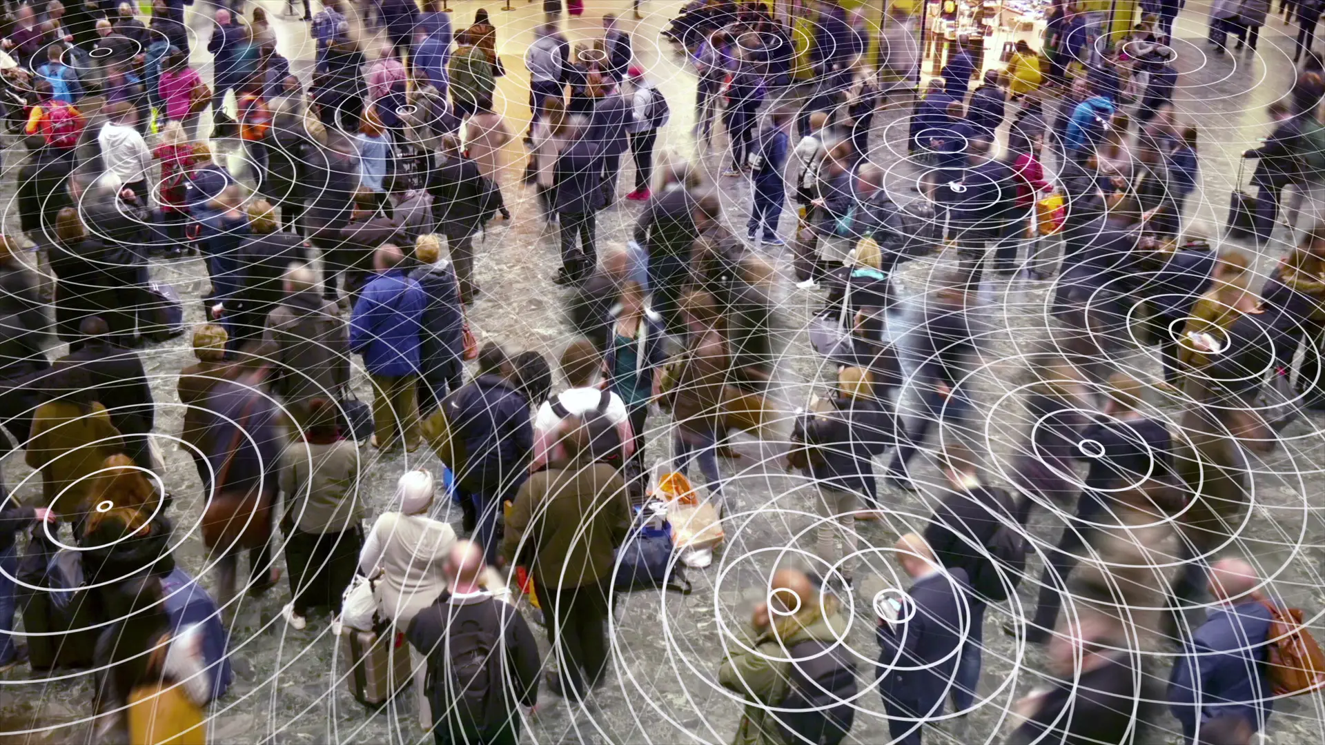 Crowd of people in a busy public space with visual representation of electromagnetic fields, highlighting concerns related to non-ionizing EMFs and health.